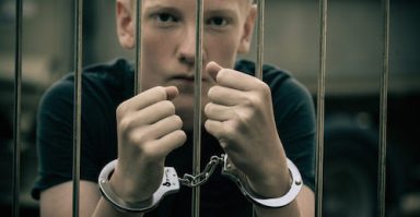 Handcuffed Teenage Boy Behind Bars
