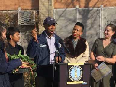 Borough President Adams taking a bite out of swiss chard grown at the hydroponic farm at PS 56