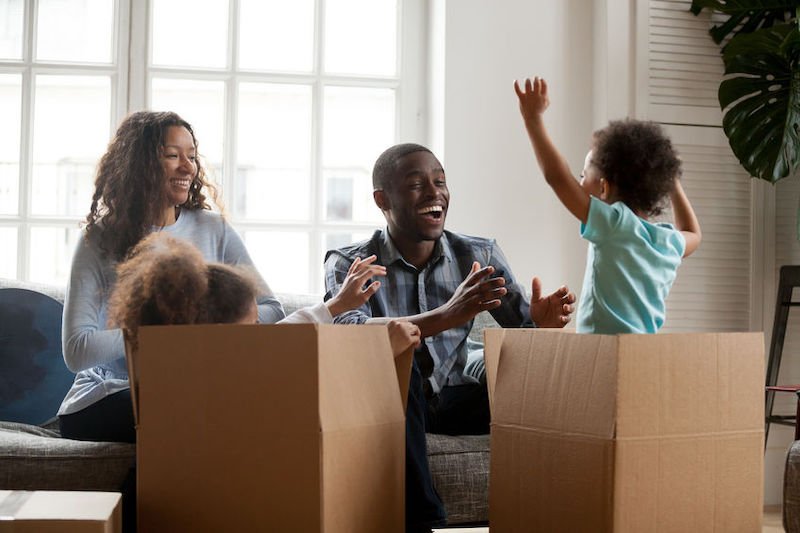 Excited mixed-race kids jumping out of box playing with parents
