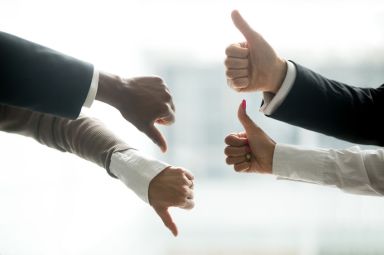 Hands of diverse business people showing thumbs up and down