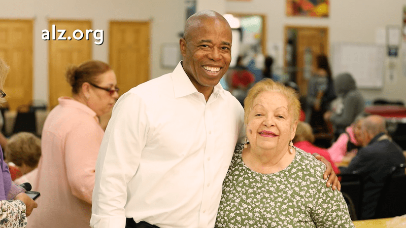 Eric Adams with woman alz org over shoulder