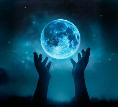 Abstract hands while praying at blue full moon with star in dark