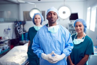 Portrait Of Multi-Cultural Surgical Team Standing In Hospital Operating Theater. Photo from 123rf Stock Photo.