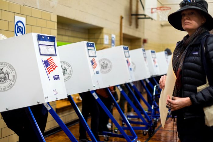 A woman holding her ballot waiting to for a partition voting unit to open up to vote.