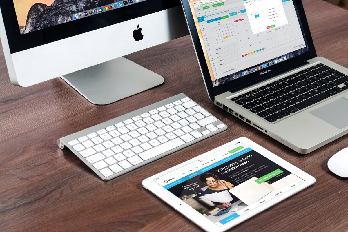 Apple desktop, laptop and tablet on a wooden desk