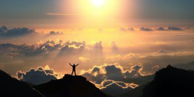 43440565 – a man standing on the top of the mountain above the clouds.