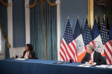 Mayor de Blasio at a media availability at City Hall with a woman from the Minority and Women-Owned Business initiative to his right.