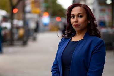 Johanna Garcia out on the street in blue blazer facing the camera, out on the street, but the background is blurred in bokeh.