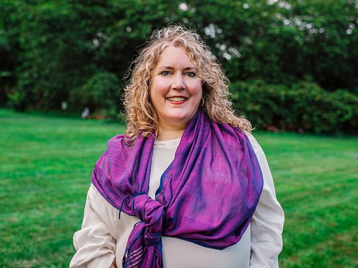 Elizabeth Caputo wearing a purple scarf, smiling to the camera at a park