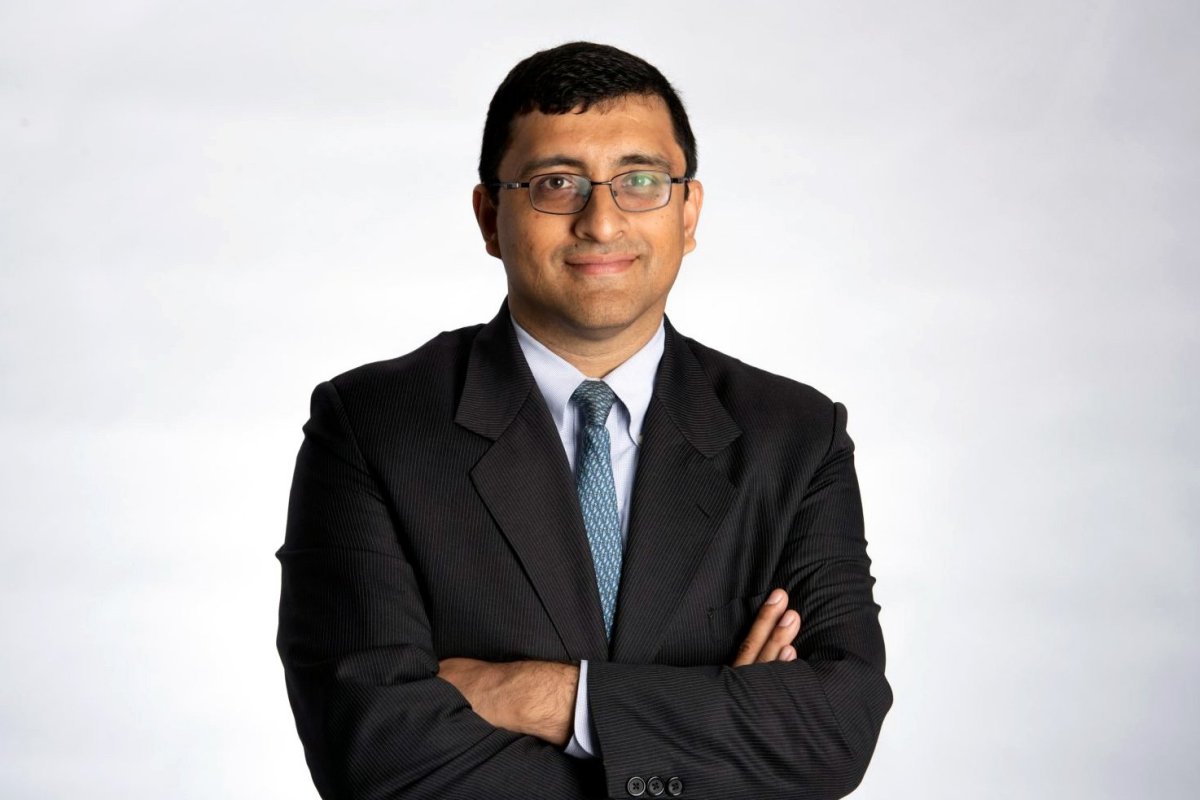 Kapil Longani in suit, a slight smile with his arms crossed