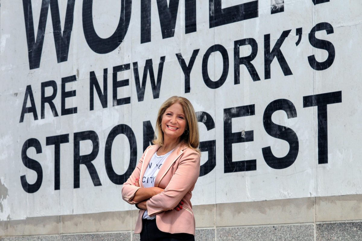 Leslie Boghosian Murphy posing to the camera in front of large mural that reads "Women are new yorker's strongest" sign.