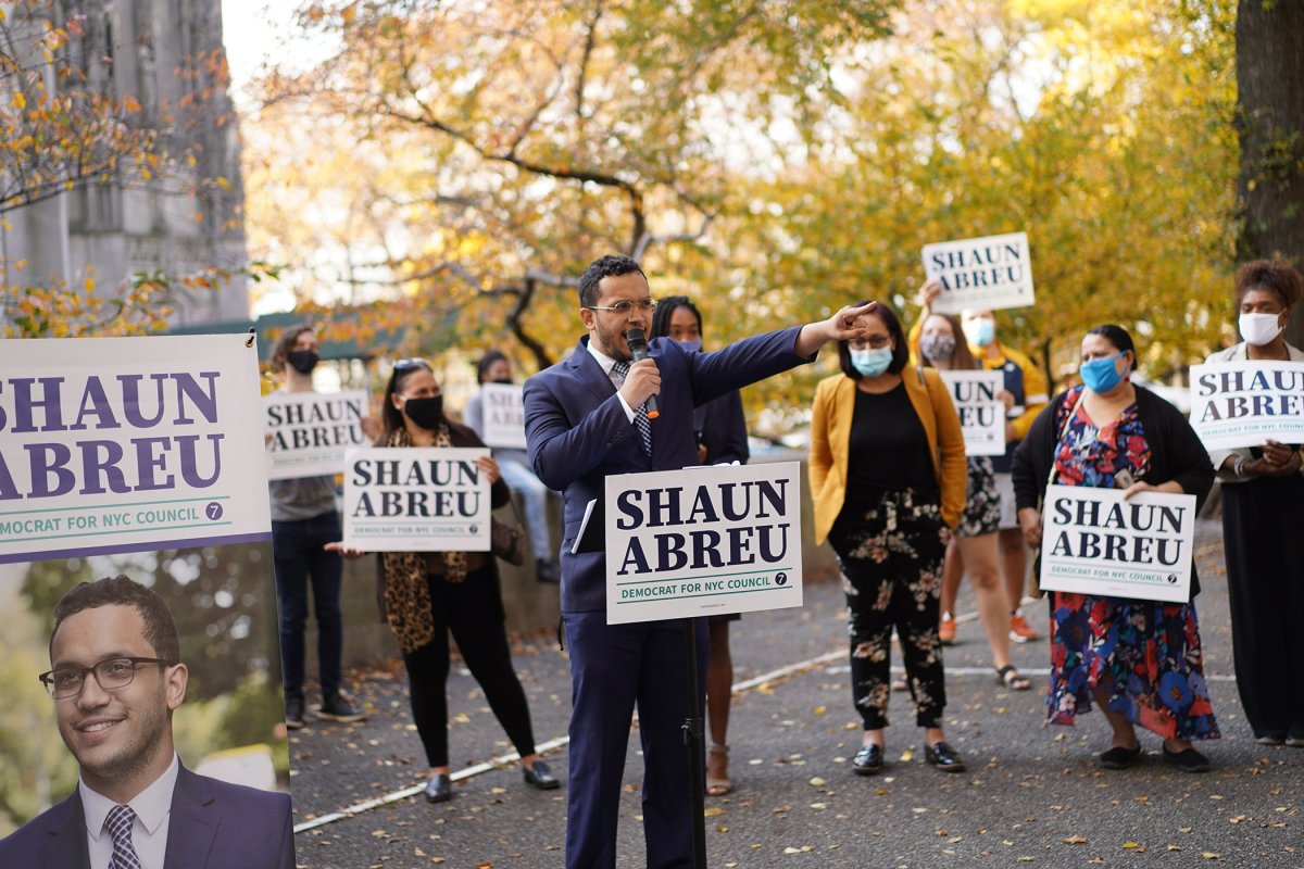 Shaun Abreau speaking on mic surrounded by his supporters at Sakura Park in Upper West Side.