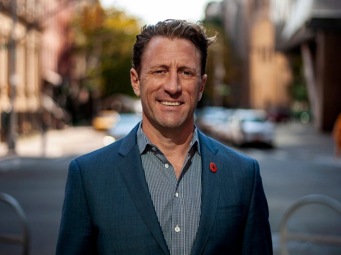 Zach Iscol in suit, outdoor on a street in New York, a slight smile to the camera